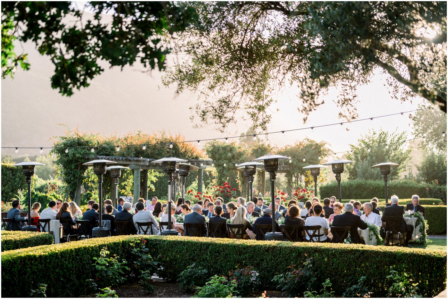 Wedding guests eating dinner with sunset and mountains behind them at bernardus wedding